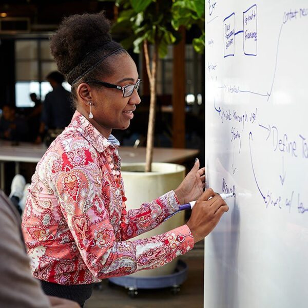 Woman working out a problem on a whiteboard.