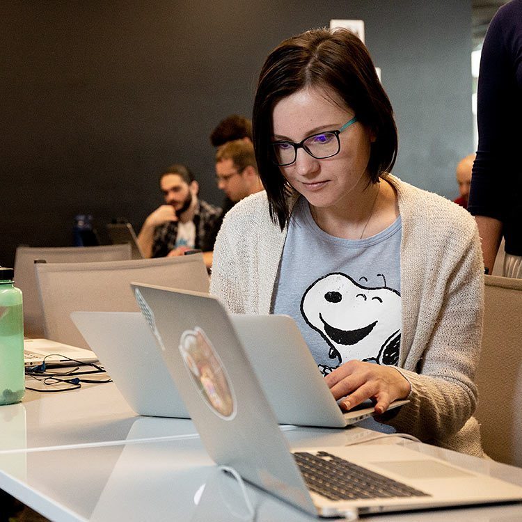 Woman wearing a Snoopy shirt looking at her laptop.