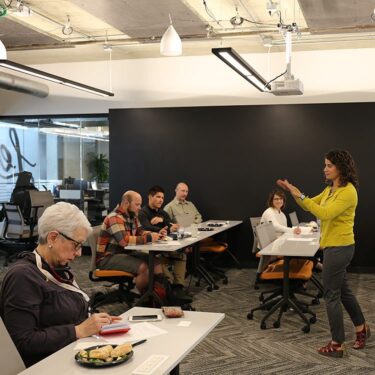 Woman leading a programming class to a group of five people.