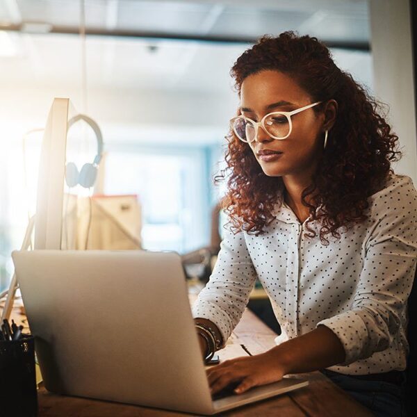 Woman wearing glasses while working on her laptop.