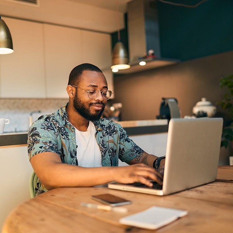 Man wearing glasses while smiling and looking at his laptop.