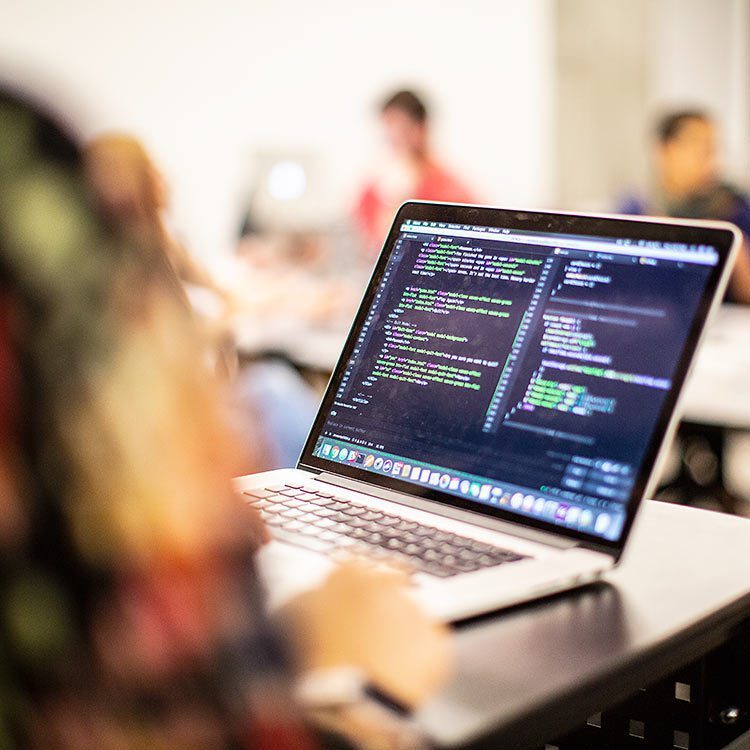 Laptop sitting on a desk with the screen filled with coding.