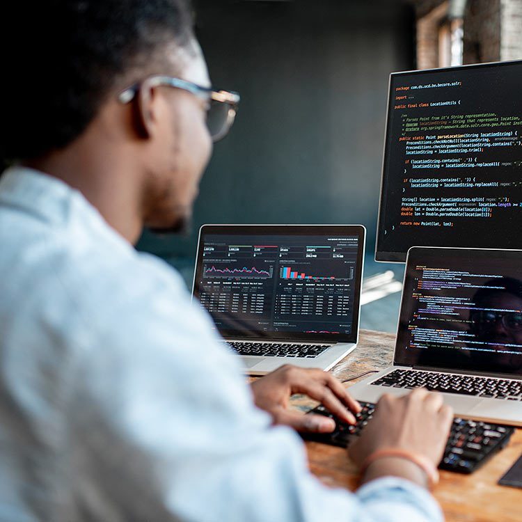 Person coding on computer using three screens.