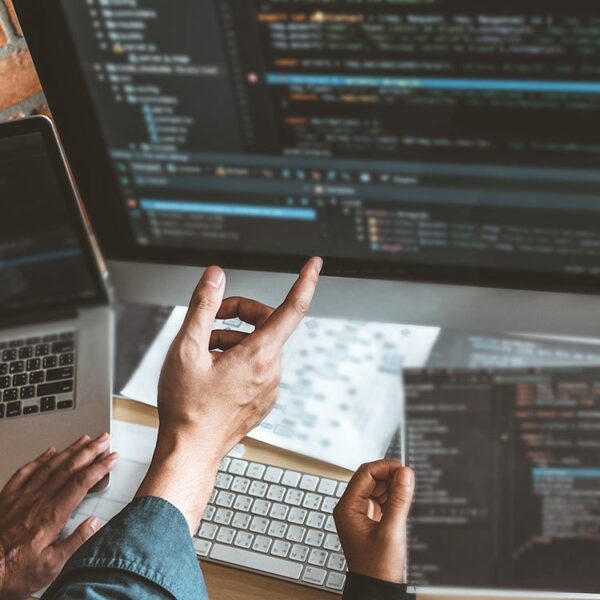 Close up hand pointing to a computer screen showing coding work.