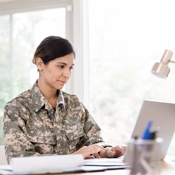 Woman in military uniform typing on her laptop.