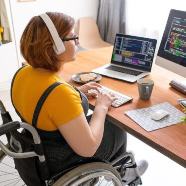 A woman in a wheelchair coding on her laptop.