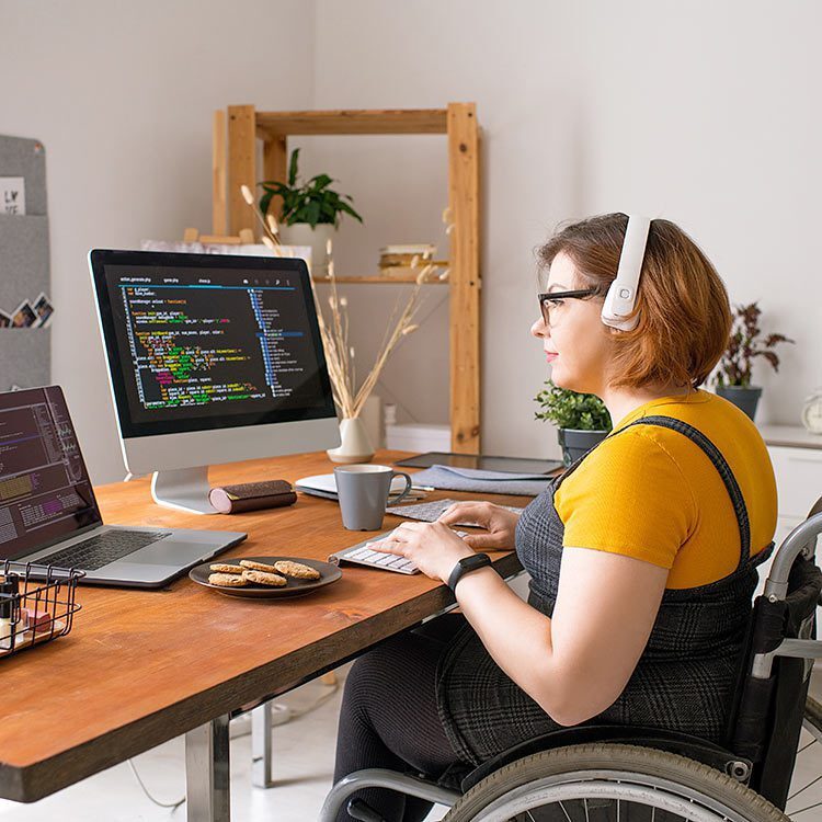 Woman in wheelchair working on coding project on her computer.