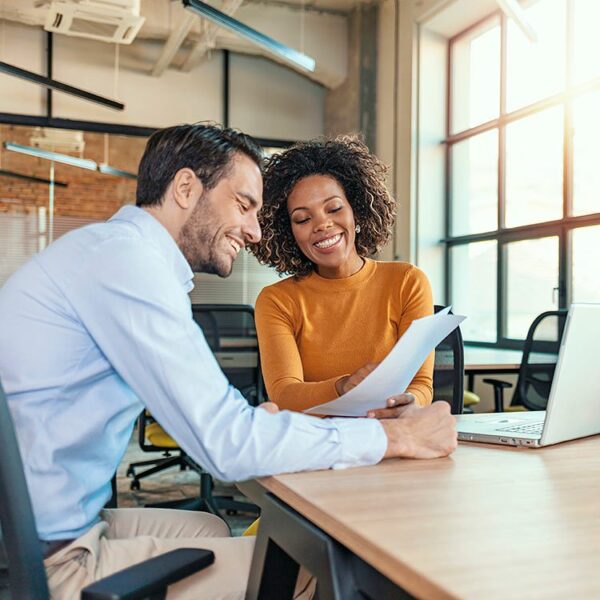 Man and woman smiling looking at a paper document together.