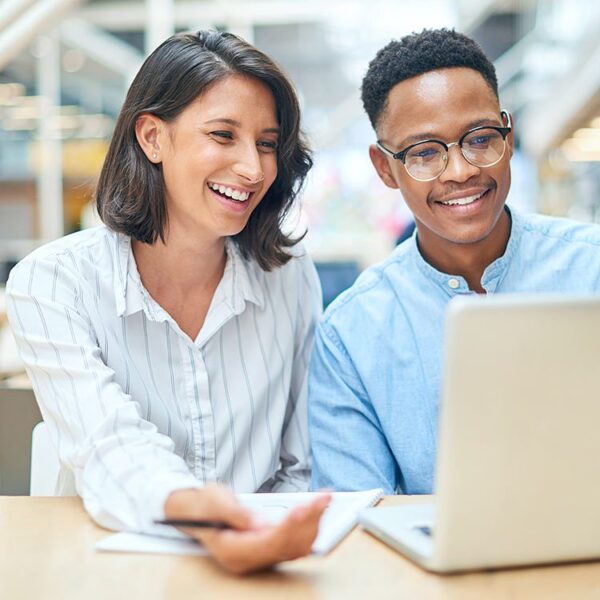 Man and woman smiling looking at a laptop screen together.