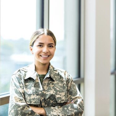 woman smiling looking at the camera in a military uniform.