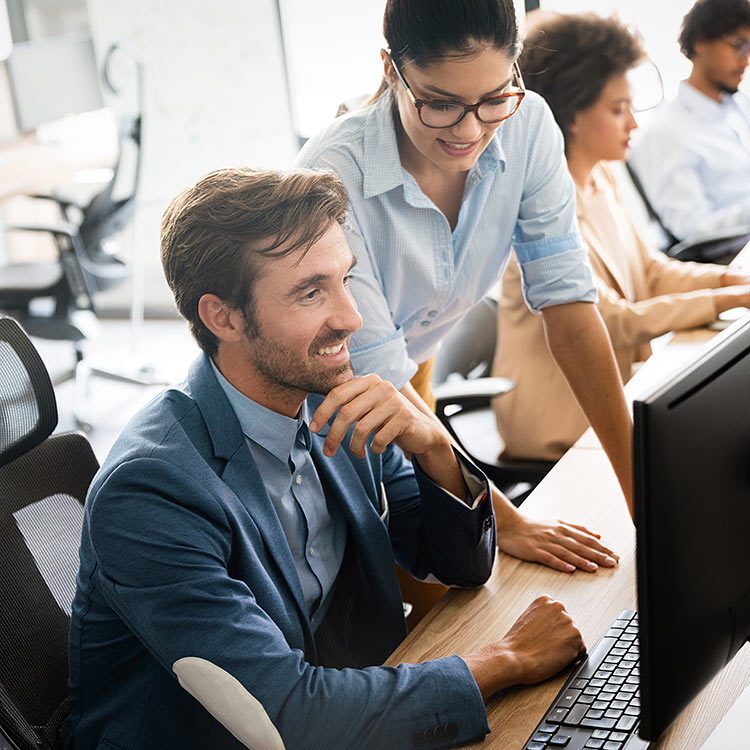 Man and woman smiling staring at computer screen.