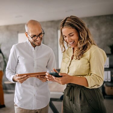 Man and woman laughing looking at her phone screen.