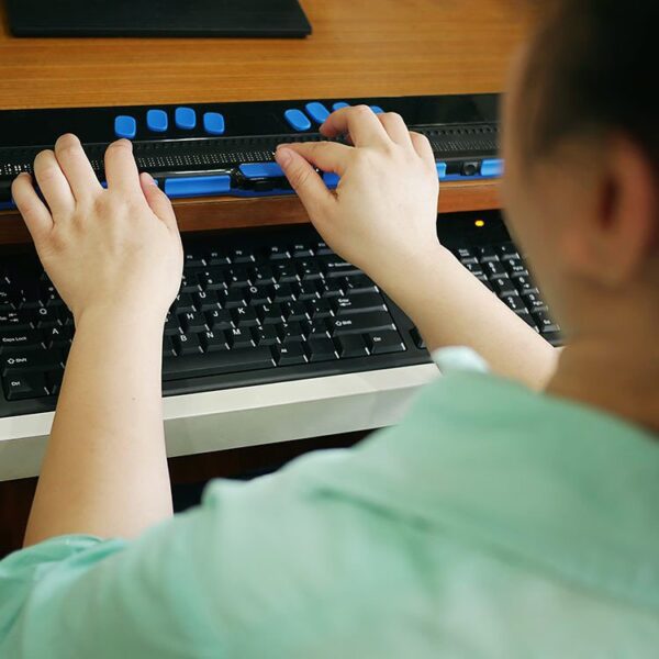 Woman using braille keyword to type on her computer.