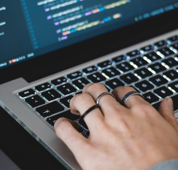 Close up of hand typing code on computer